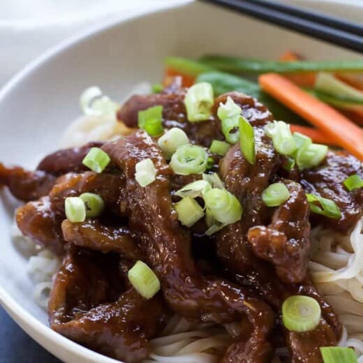 A close-up shot of honey sriracha Mongolian beef garnished with a sprinkle of scallions