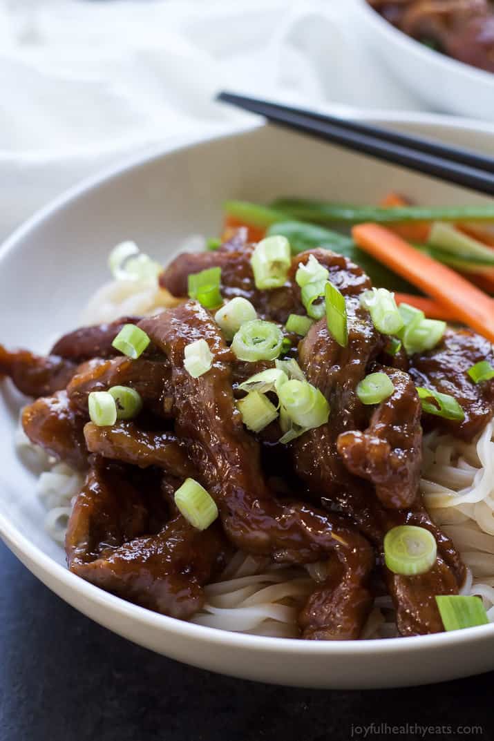 A close-up shot of honey sriracha Mongolian beef garnished with a sprinkle of scallions