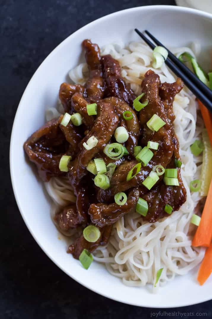 An overhead shot of honey sriracha Mongolian beef on a serving plate with sliced green onions on top
