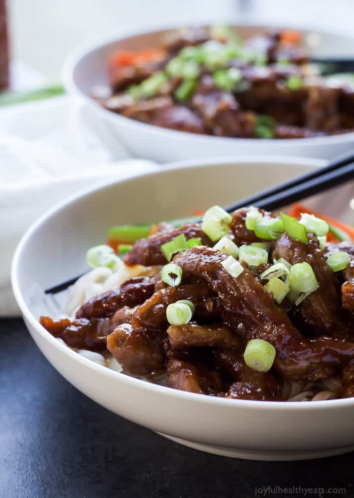 Sweet and spicy Asian-style steak in a bowl along with rice noodles and raw veggies