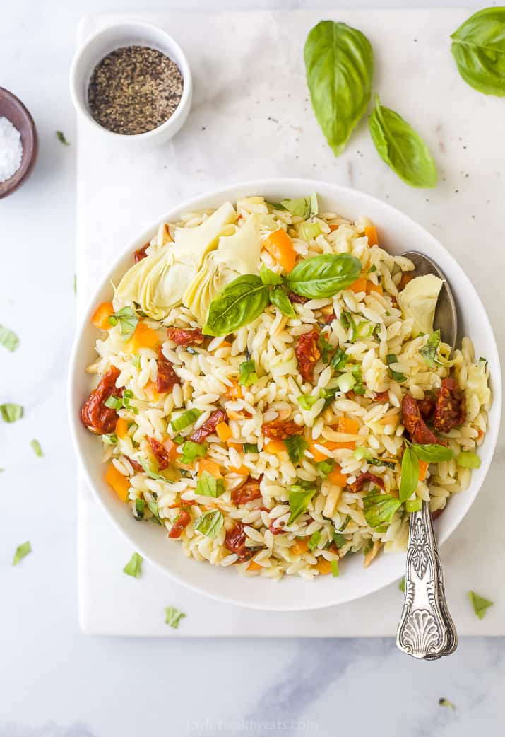 A Bowl of Orzo Salad on a Countertop with Spices and Herbs