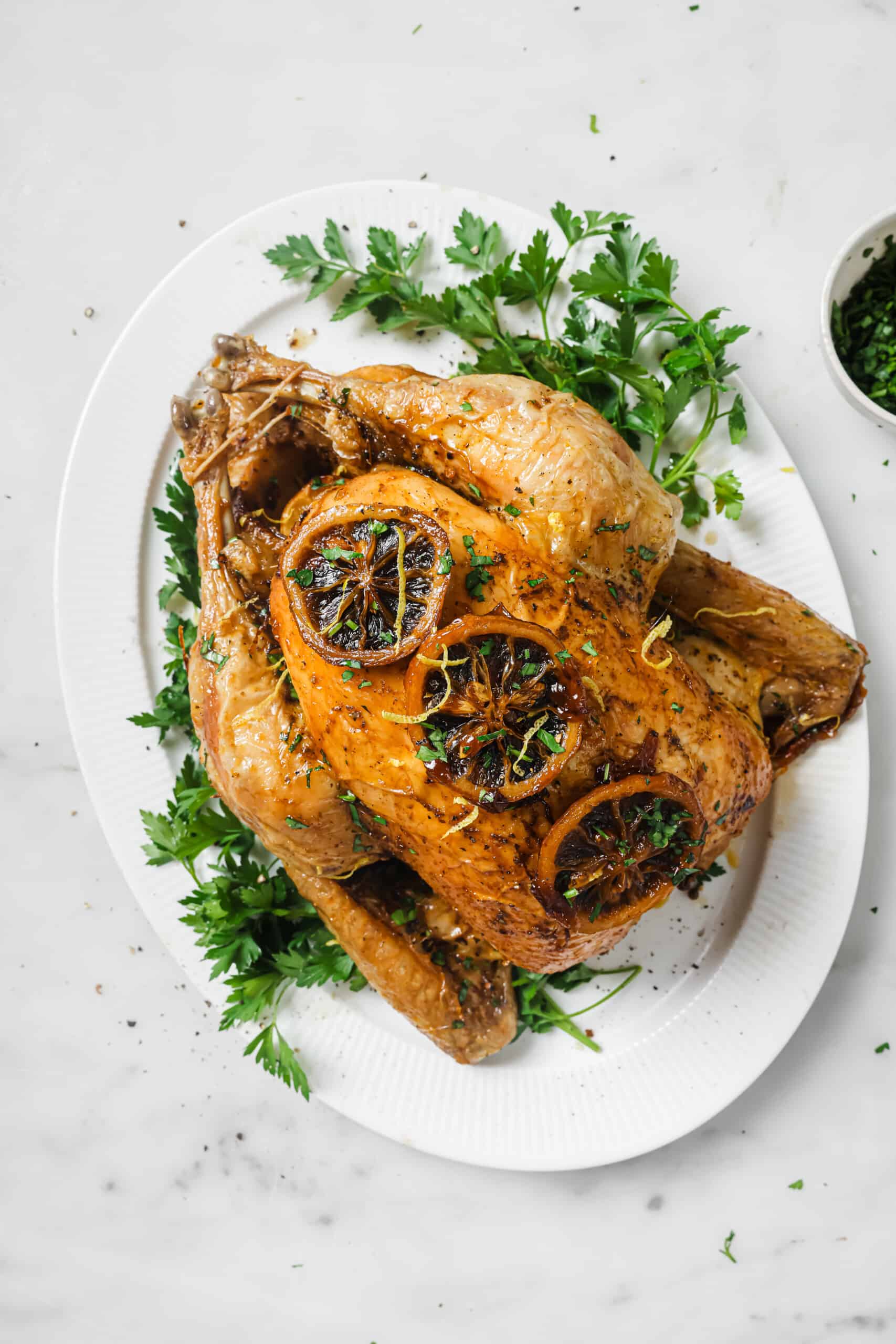With crispy skin and zesty butter, this bake-and-forget roasted chicken recipe will be a weeknight favorite! Oven roasted chicken on a serving plate.