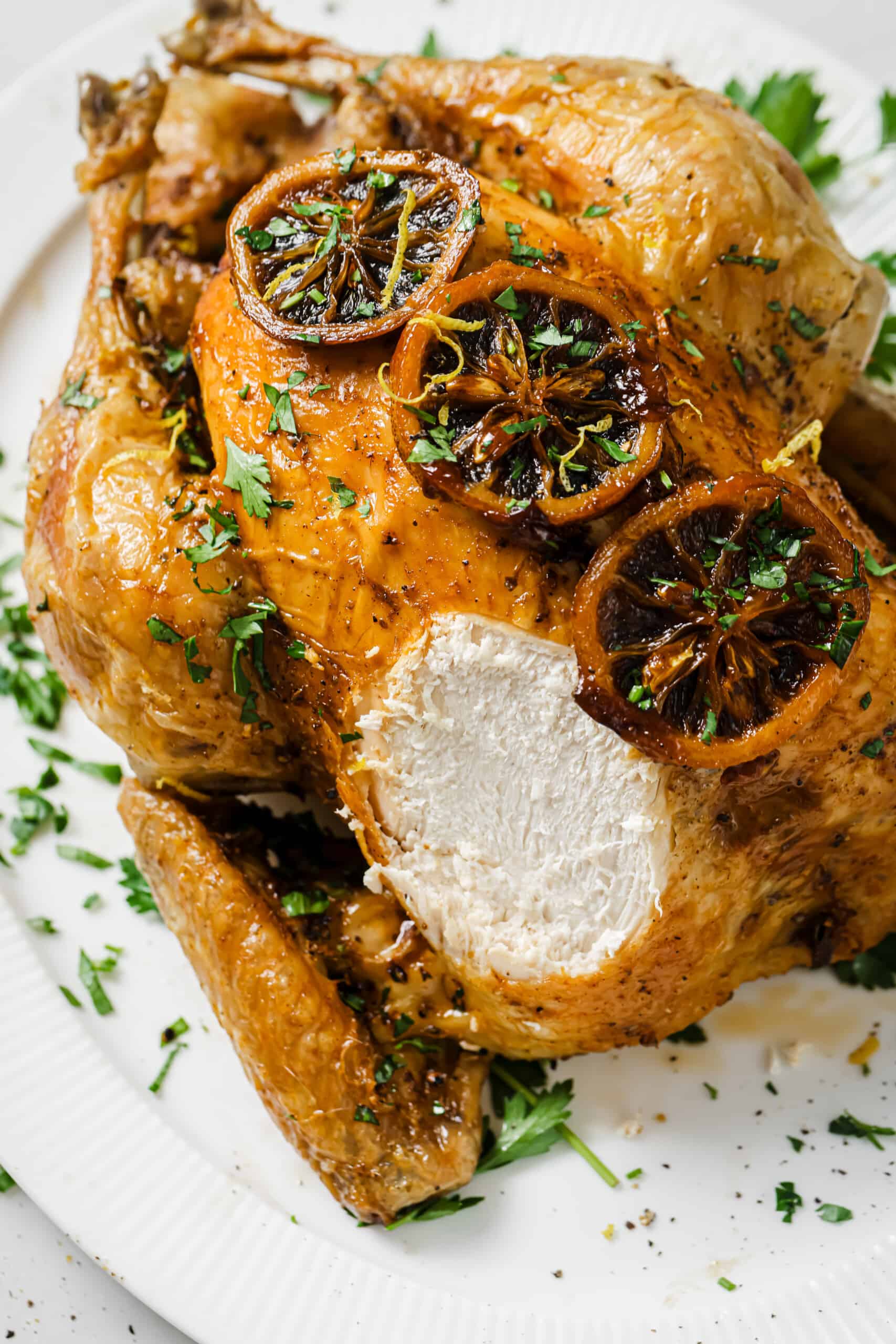 With crispy skin and zesty butter, this bake-and-forget roasted chicken recipe will be a weeknight favorite! Whole roasted chicken with a chunk sliced off.