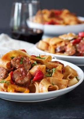 Three servings of tomato pappardelle pasta with a glass of red wine beside them