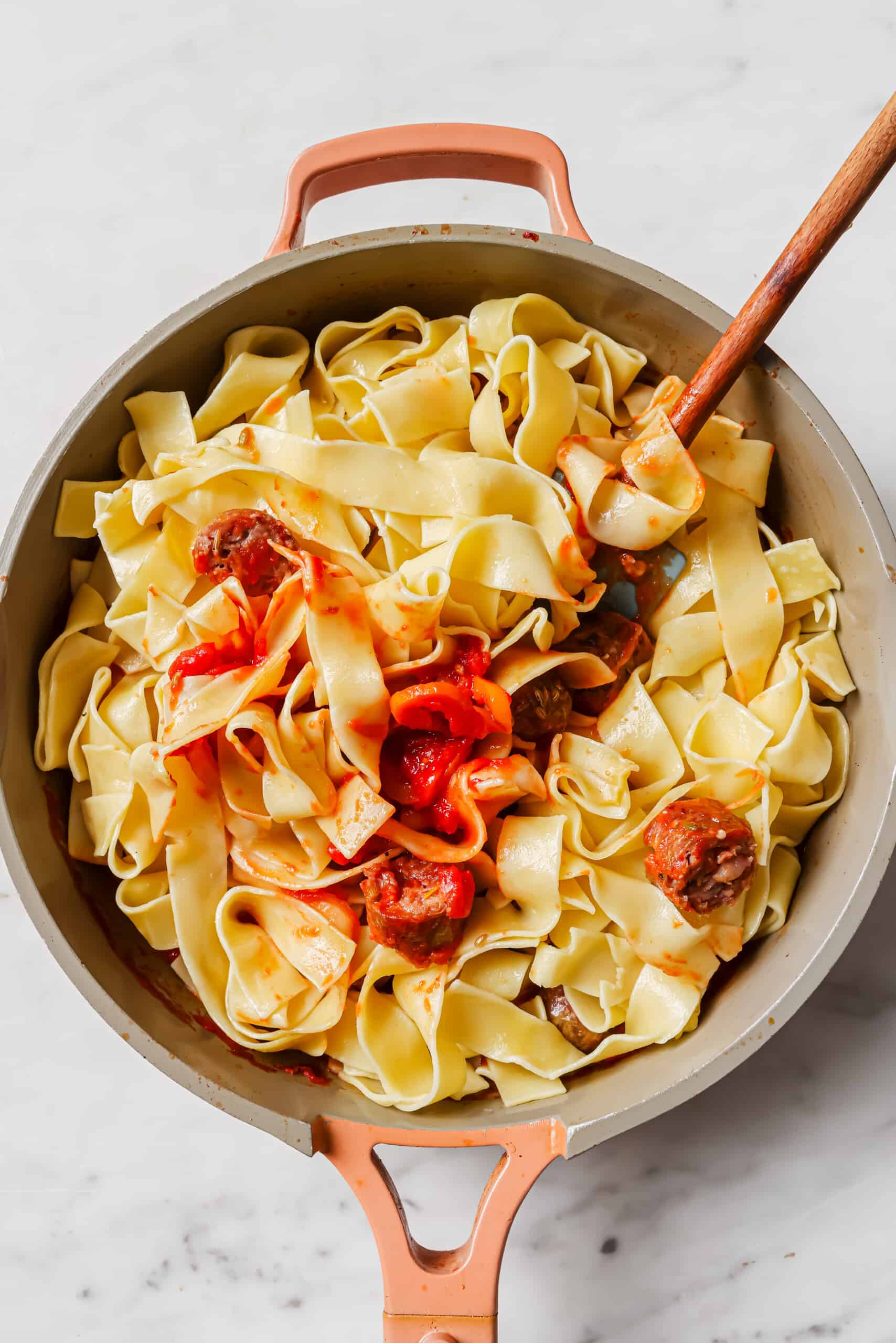 Stirring the pasta into the sauce.