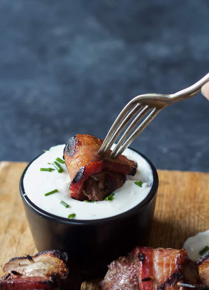 A Bacon Wrapped Tenderloin Bite being dipped into creamy horseradish sauce