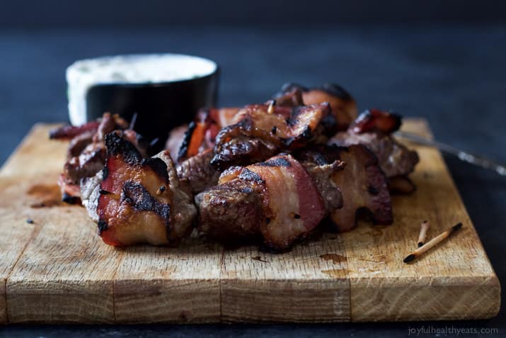 Chargrilled Bacon Wrapped Tenderloin Bites on a cutting board with creamy horseradish sauce