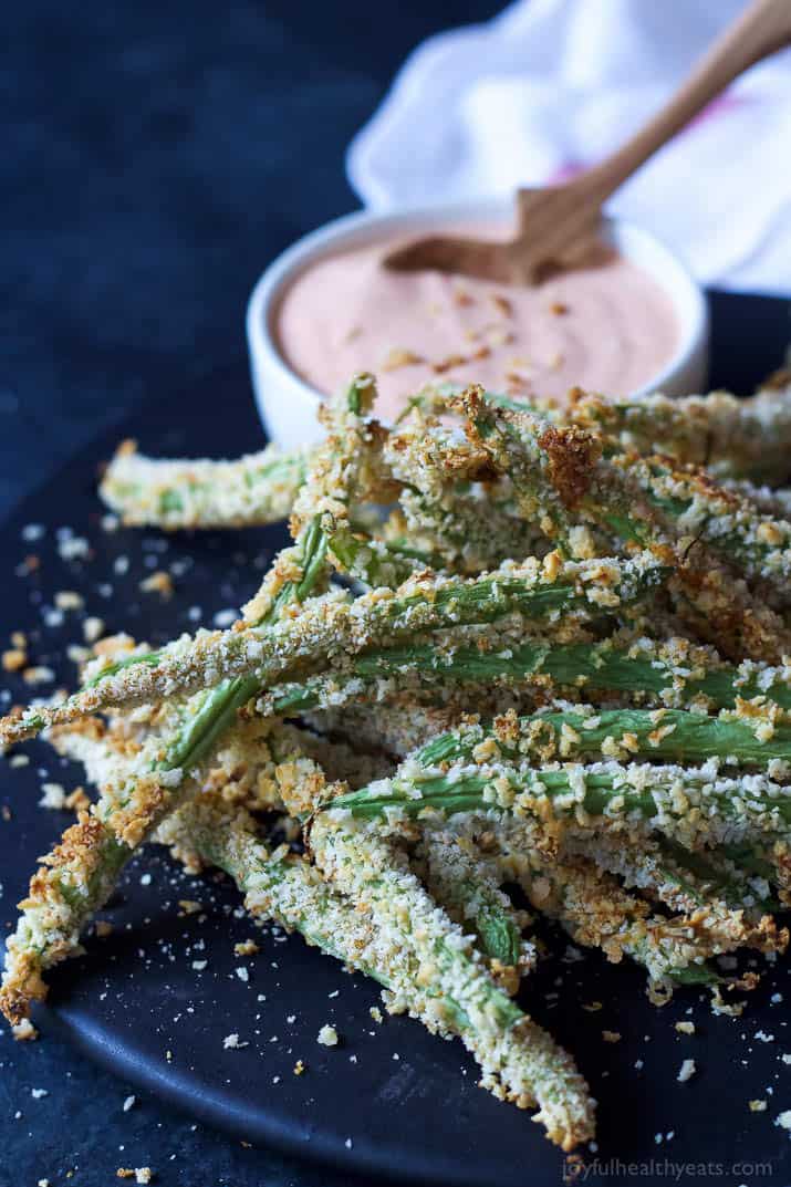 Crispy Baked Green Bean Fries on a plate with a cup of Creamy Sriracha Sauce for dipping