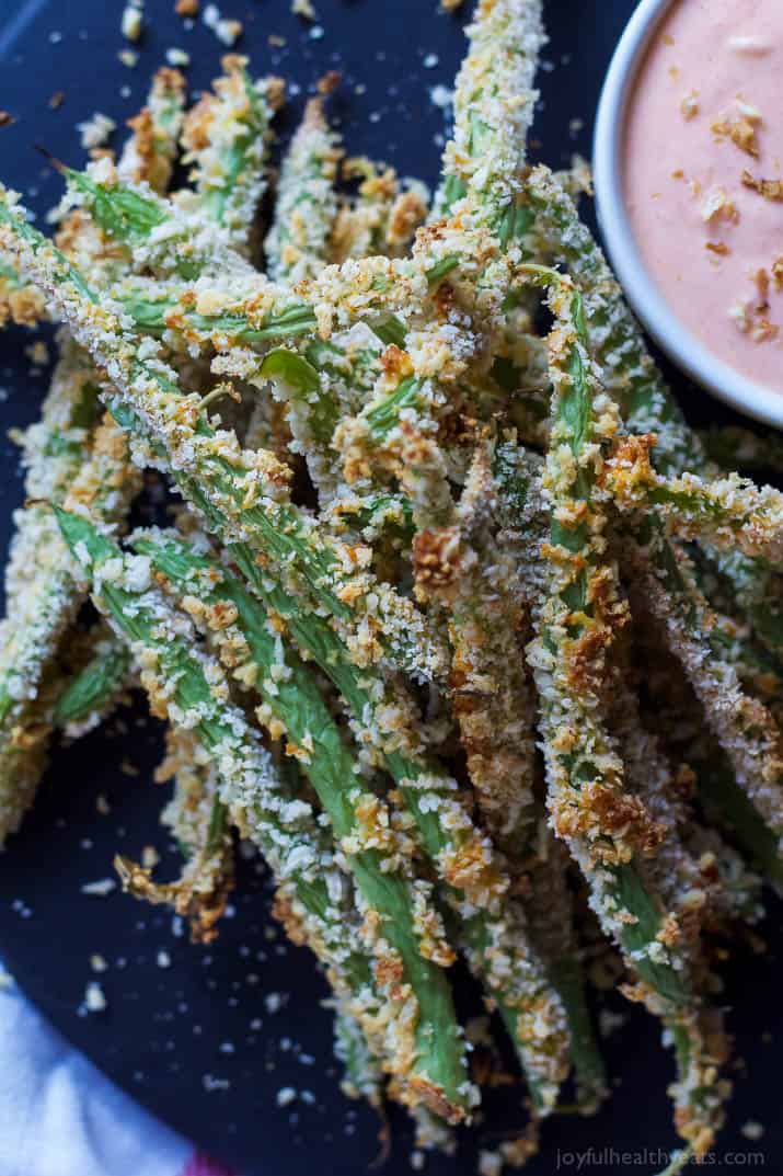 Top view of Crispy Baked Green Bean Fries with a cup of Creamy Sriracha Sauce for dipping