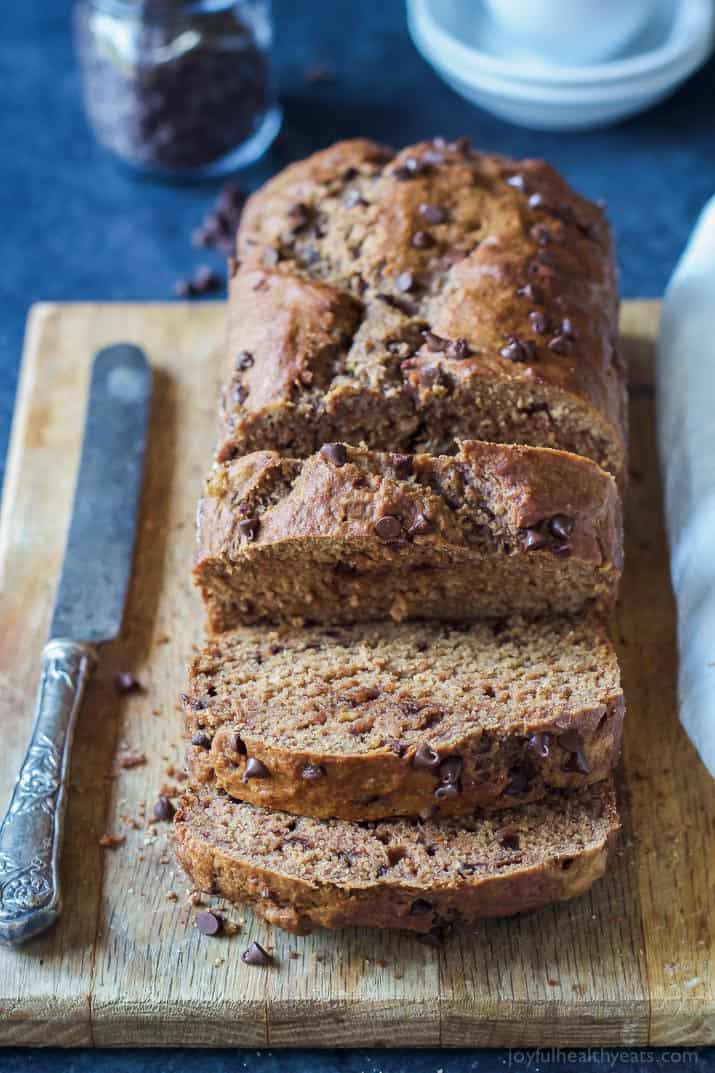 A partially-sliced loaf of Double Chocolate Banana Bread on a wooden cutting board