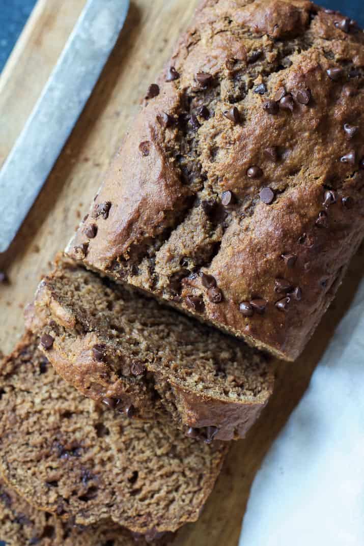 Top view of a loaf of Double Chocolate Banana Bread with a couple slices on a wooden cutting board