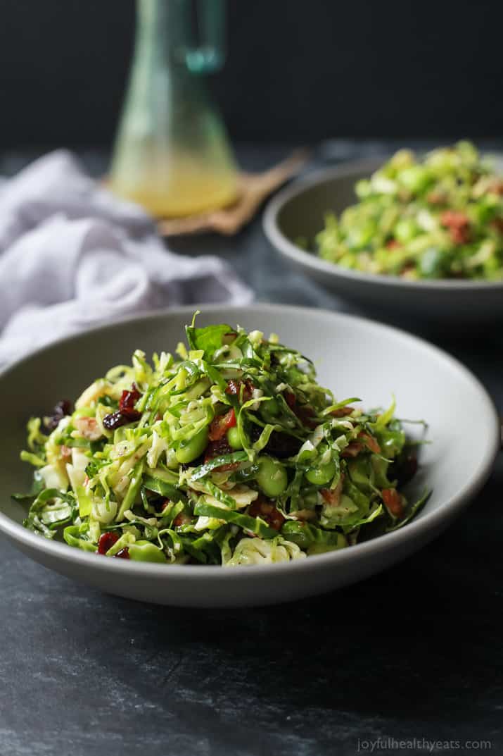 Autumn Kale & Shaved Brussel Sprout Salad with bacon and edamame in a bowl