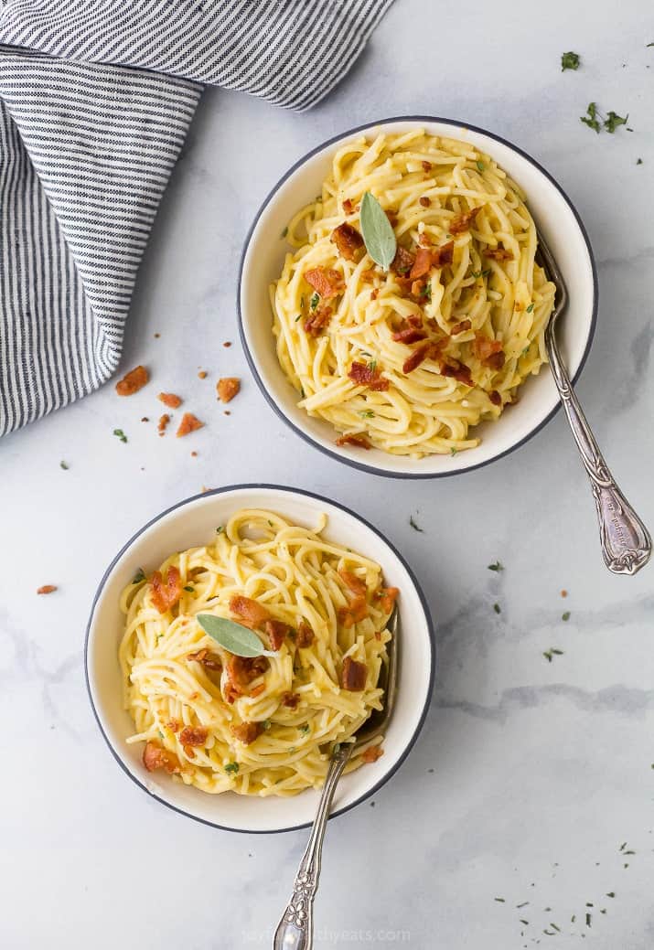 Top view of two bowls of creamy butternut squash pasta with bacon