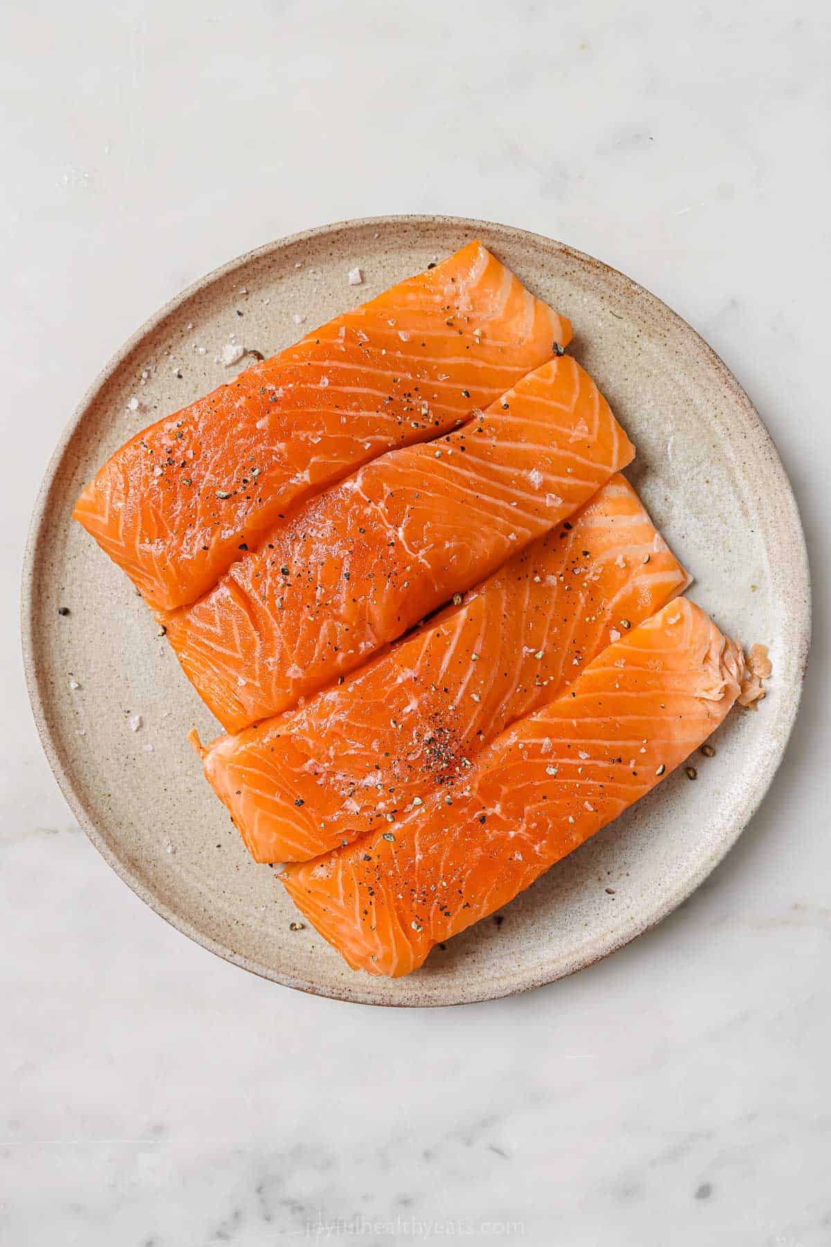 Seasoning the salmon with salt and pepper. 