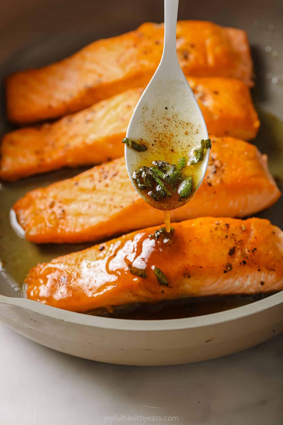 Drizzling brown butter sauce over the pan seared salmon. 