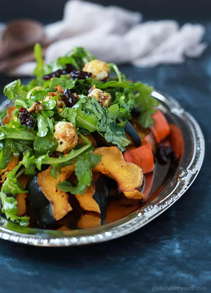 A perfect vegetarian side dish for the fall, Roasted Acorn Squash topped with a fresh Arugula Salad that's mixed with dried cherries and goat cheese balls coated with salty pistachios. De-lish! | joyfulhealthyeats.com #recipes #glutenfree #vegetarian