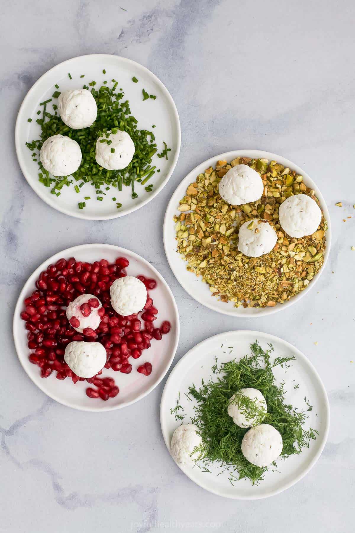 Four rimmed plates holding various toppings and three cheeseballs each