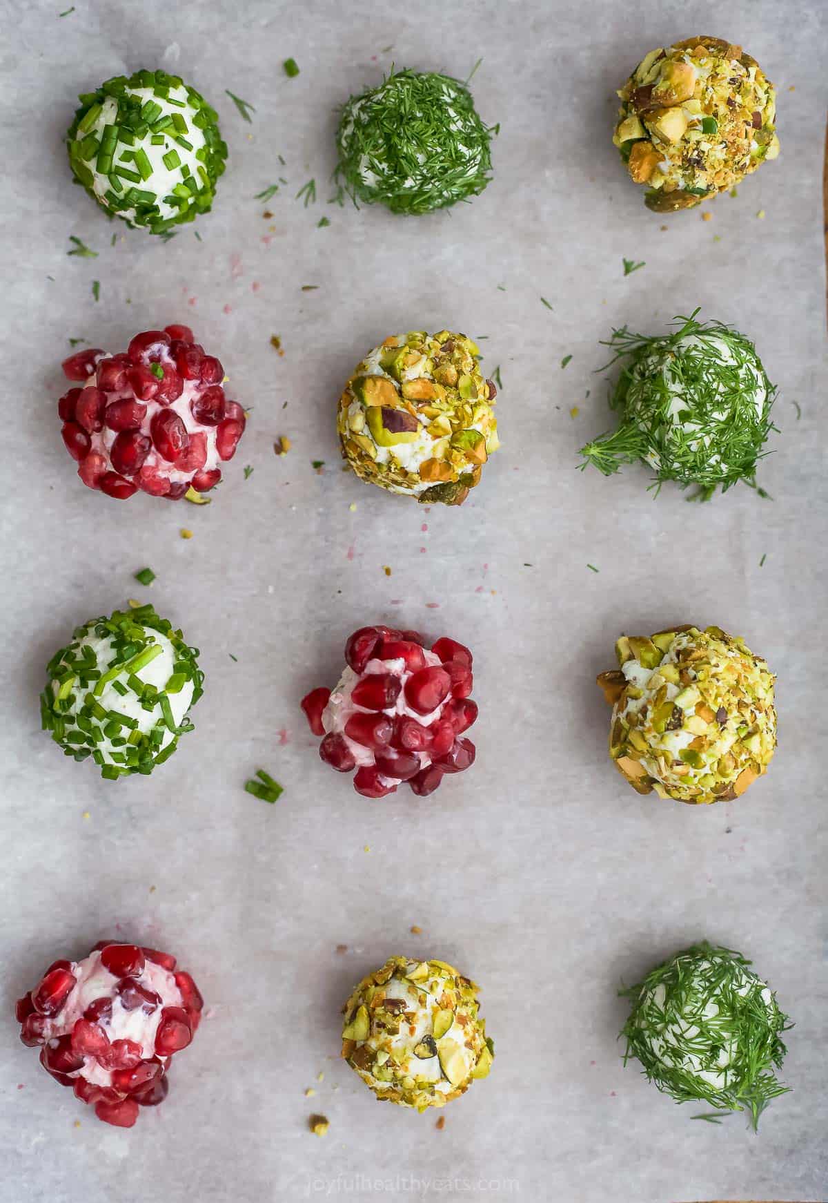 Cheeseballs with various toppings lined up on a sheet of parchment paper and shown from above