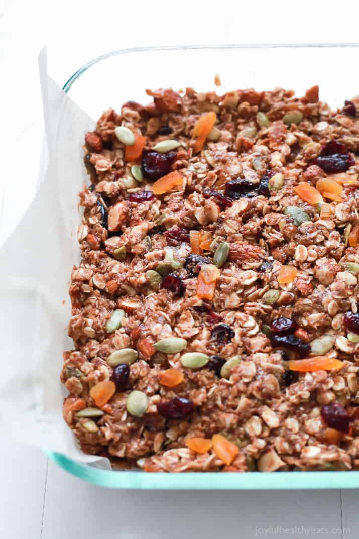 A parchment-lined baking dish filled with the set granola bar mixture