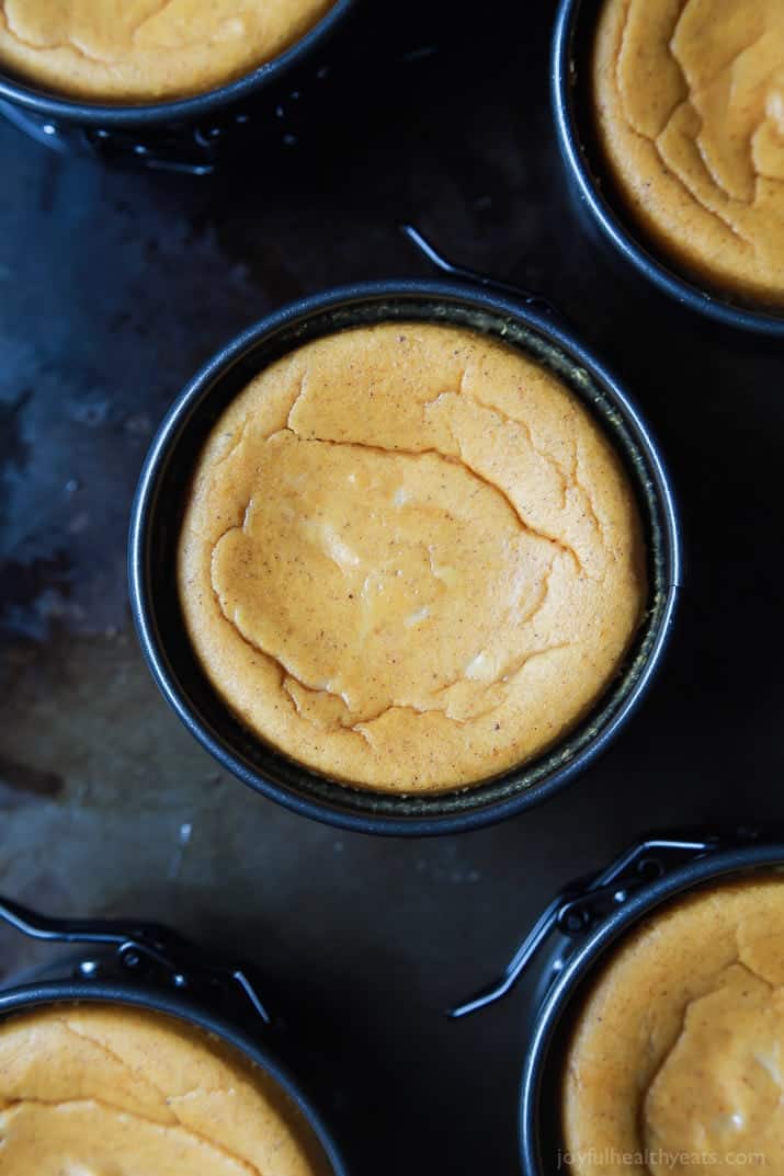 A fully baked cheesecake in a mini springform pan on top of a baking sheet