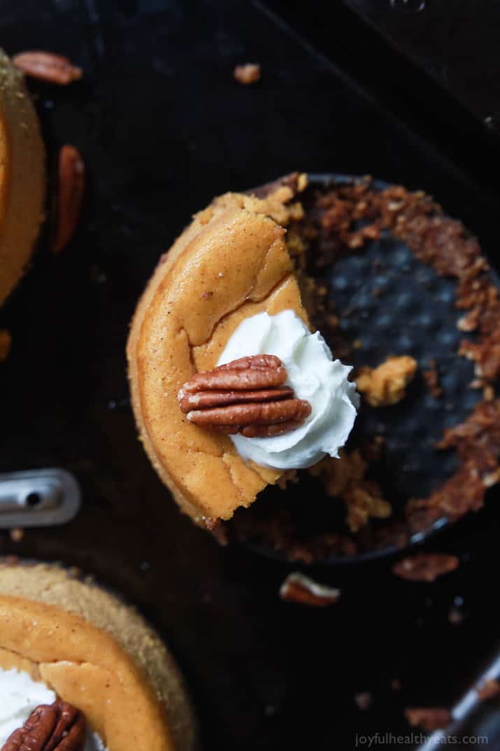 A quarter of a mini pumpkin cheesecake with a dot of whipped cream and a single pecan on top