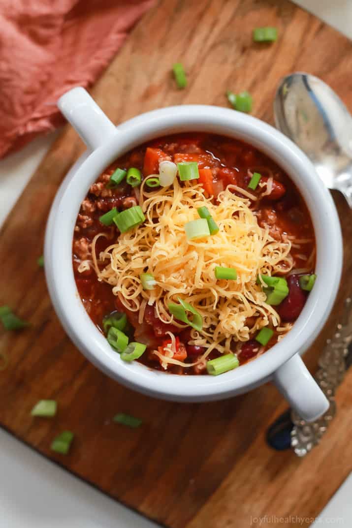 A bowl of turkey chili topped with shredded cheese and green onions.