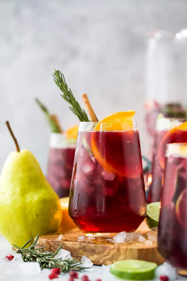 the ultimate holiday sangria recipe in a glass with ice and garnishes