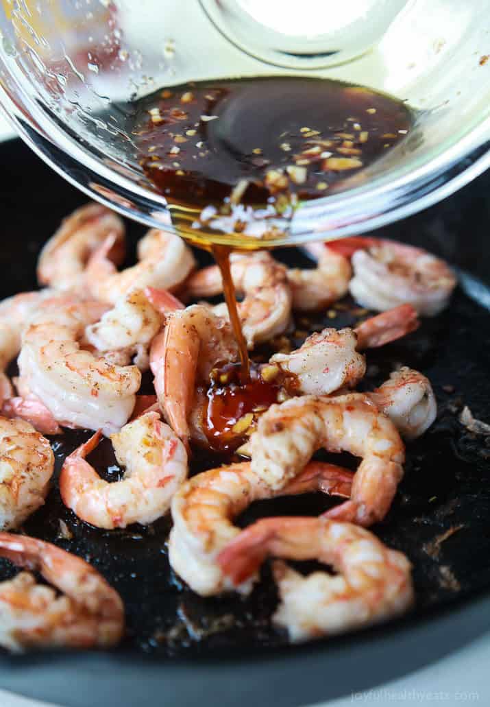 Honey Garlic Sauce being poured over sauteed shrimp in a skillet