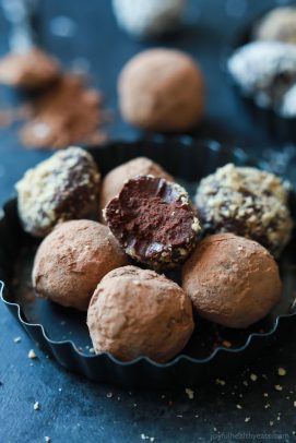 A bowl full of Decadent Healthy Chocolate Truffles with a bite taken out of one of them.