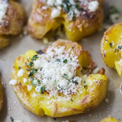 Close-up of smashed potatoes with garlic-herb mixture on top.