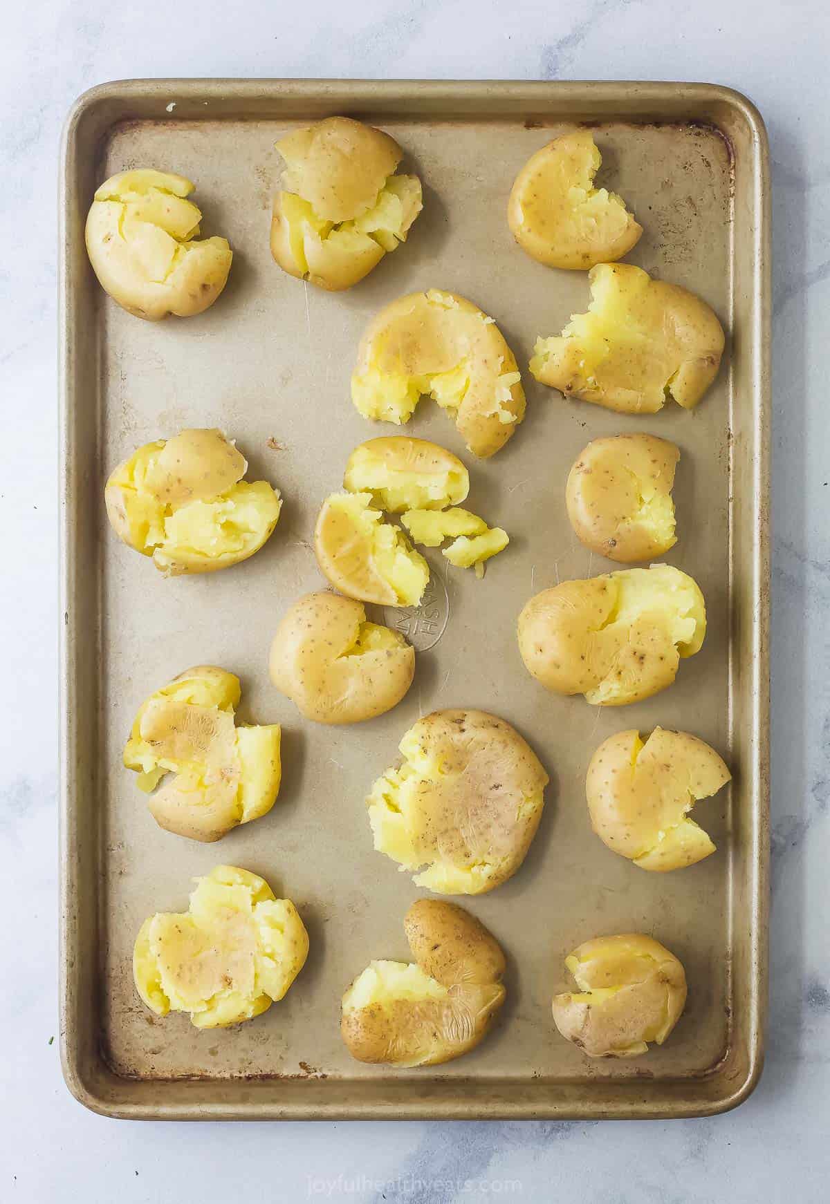 Smashing the potatoes on the baking sheet. 