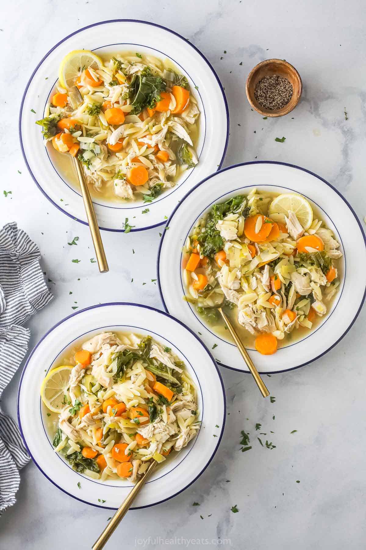 Three bowls of lemon chicken orzo soup. 