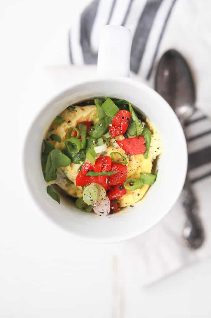 Top view of egg omelet in a mug with scallions and red peppers