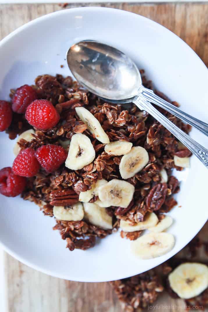 Top view of Homemade Banana Bread Granola in a bowl with dried banana slices and fresh raspberries