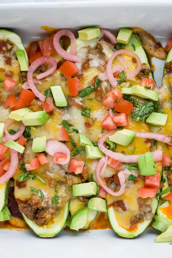 Overhead view of enchilada zucchini boats topped with onions, romatoes, and avocados