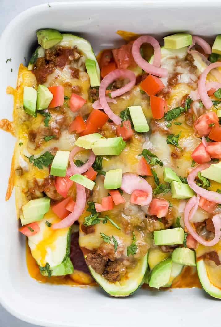 Ground beef enchilada zucchini boats topped with avocado, tomato and onions