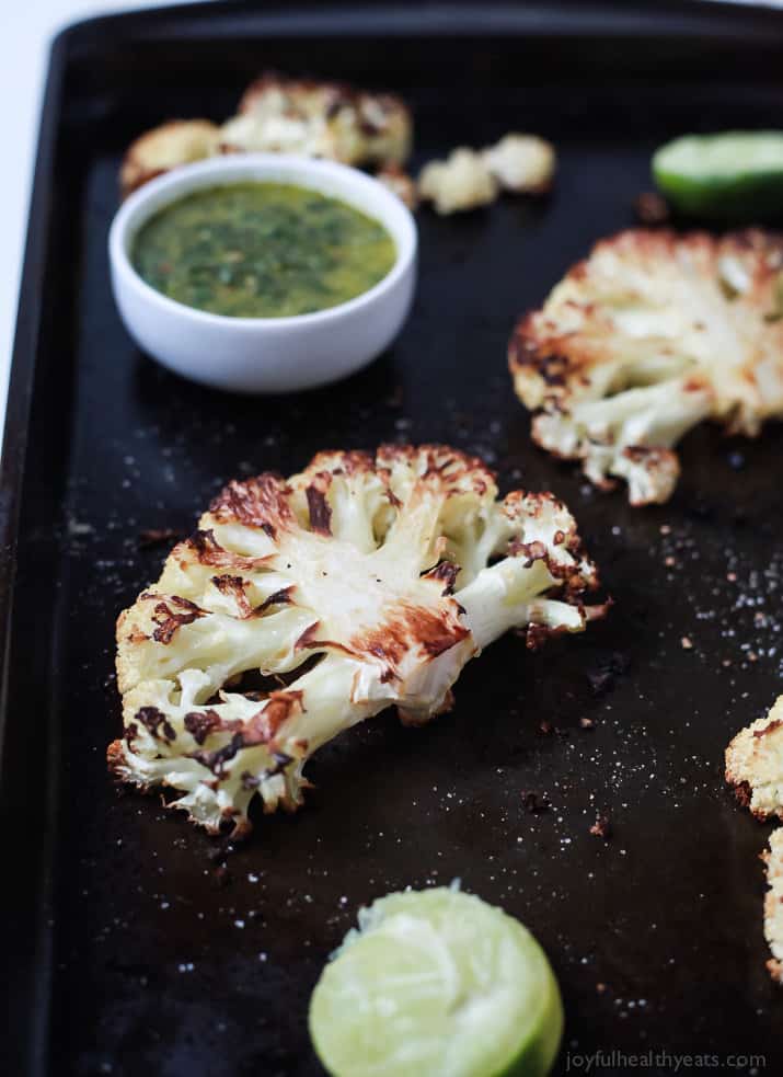 Easy naturally Gluten Free Roasted Cauliflower Steaks topped with fresh zesty Chimichurri Sauce at only 106 calories. Who knew Cauliflower could taste so good! This recipe is down right addicting! | joyfulhealthyeats.com