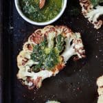 A Roasted Cauliflower Steak with Chimichurri Sauce in a Dish on the Side