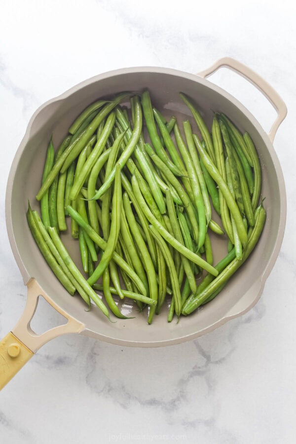 Green beans in skillet with oil.