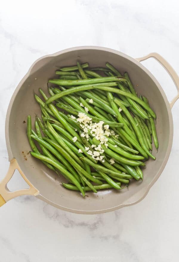 Garlic added to green beans in skillet.