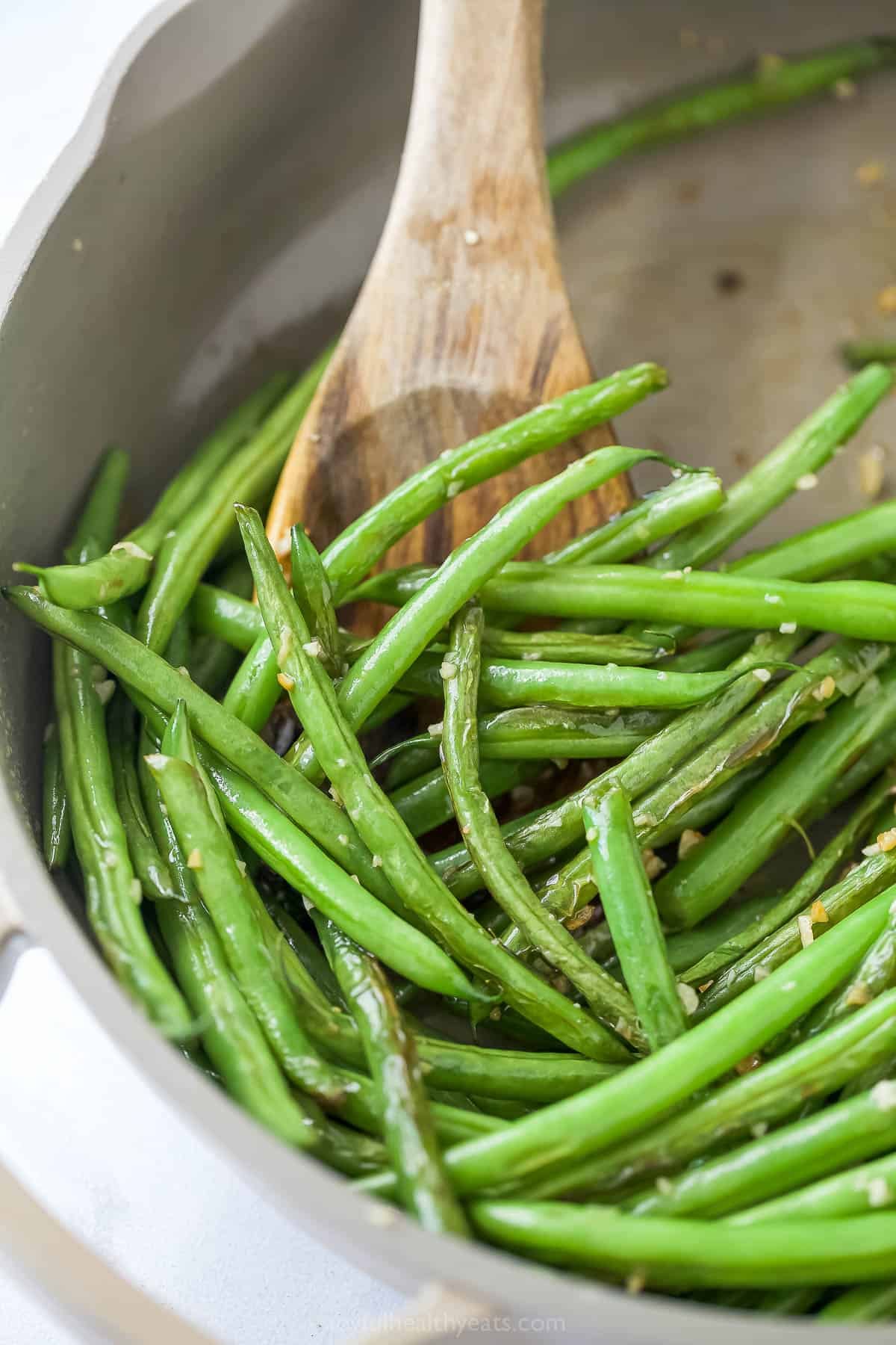 Stirring green beans in skillet.
