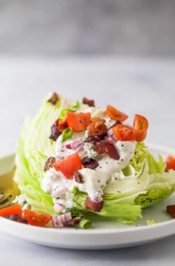 iceberg lettuce wedge with crumbled bacon, tomatoes, red onions, and blue cheese dressing