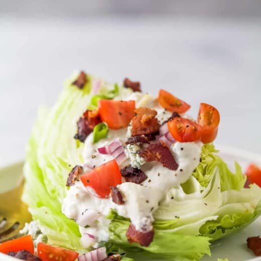 iceberg lettuce wedge with crumbled bacon, tomatoes, red onions, and blue cheese dressing