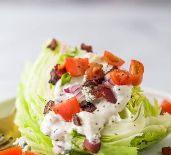 iceberg lettuce wedge with crumbled bacon, tomatoes, red onions, and blue cheese dressing
