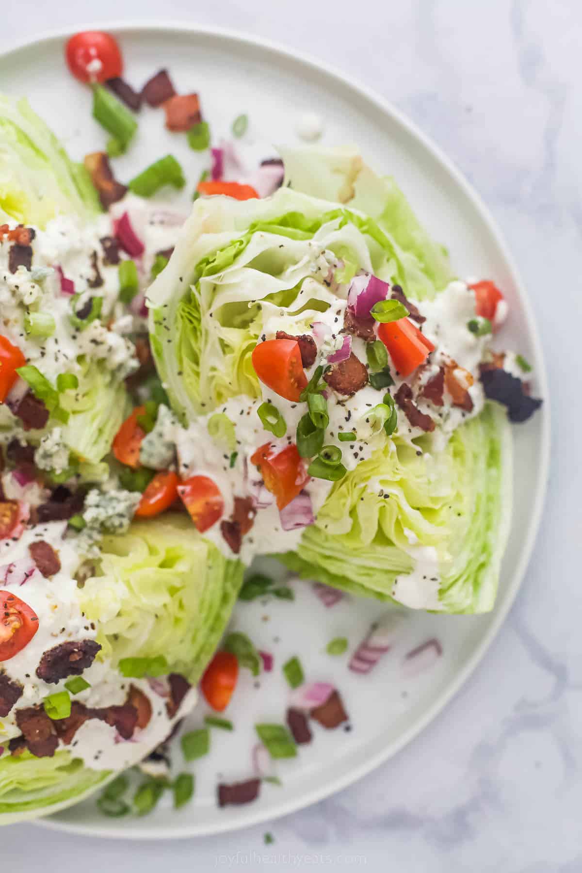 This Classic Wedge Salad with Blue Cheese Dressing is loaded with flavor from the crispy Bacon to the tangy dressing. It's light and easy! Wedge Salad with iceberg lettuce, tomatoes, bacon, red onions and creamy dressing