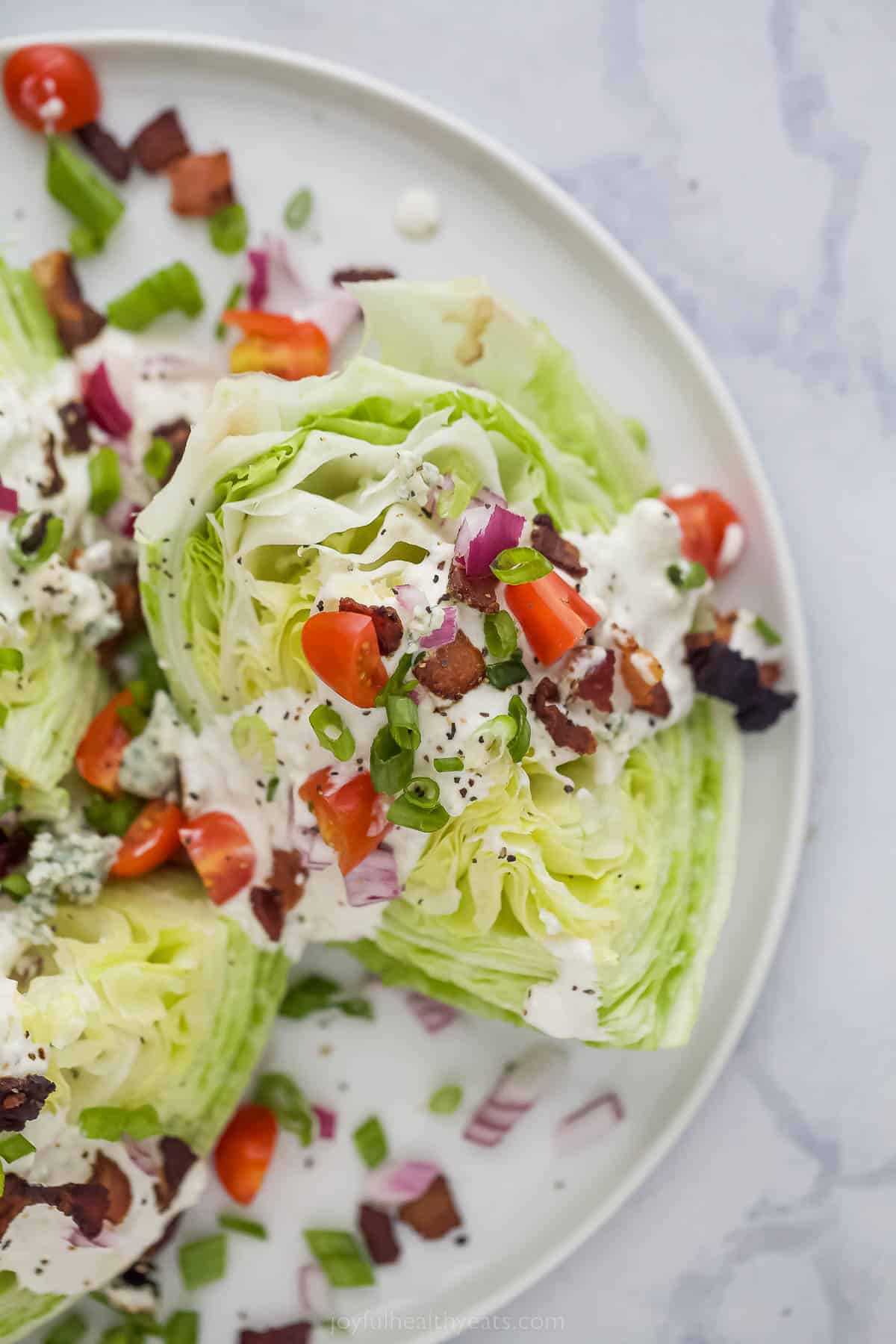 This Classic Wedge Salad with Blue Cheese Dressing is loaded with flavor from the crispy Bacon to the tangy dressing. It's light and easy! Wedge Salad with iceberg lettuce, tomatoes, bacon, red onions and creamy dressing