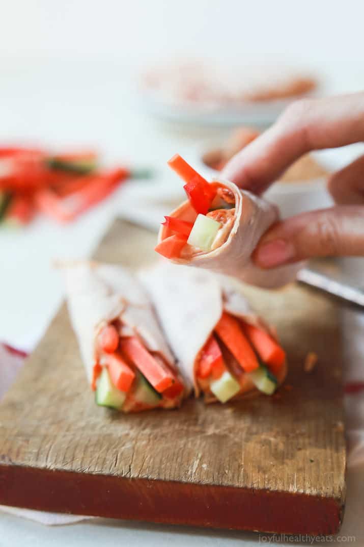 Veggie Turkey Rollups on a wooden board with one being held up