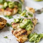 side photo of sliced grilled cilantro lime chicken topped with avocado salsa and red onion