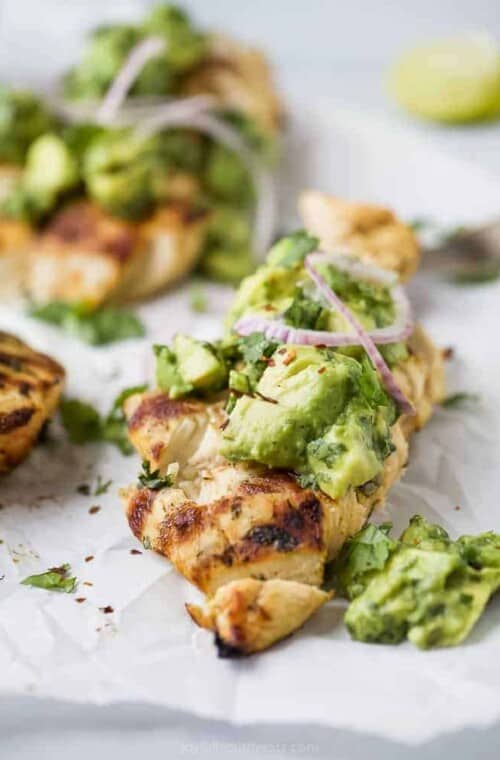 side photo of sliced grilled cilantro lime chicken topped with avocado salsa and red onion