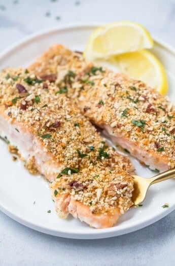 Pecan crusted salmon with lemon wedges on the side.